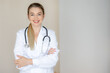 © Ivan - Confident female doctor smiling while standing with folded arms in medical uniform