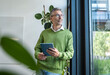 © Westend61 - Business professional in green sweater with tablet by office window