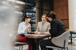 © qunica.com - Three businesswomen discussing strategy while sitting in a contemporary workplace setting.
