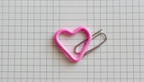 Pink heart-shaped paperclip on grid paper (2)