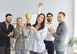 © Studio Romantic - Group of cheerful business people standing in office, holding golden trophy cup and clapping hands. Happy smiling team of employees celebrating great hard work success, triumph and goals achievement.