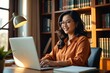 © kineter_ai - Warm, Curvy Southeast Asian Woman with Glasses Smiling at Her Laptop in a Cozy Wooden Home Office