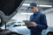 © Viktor - Young mechanic uses tablet for car diagnostics in modern garage. Focused technician checks vehicle system, using tools for maintenance, repair. Automotive service, skilled craftsmanship, professional