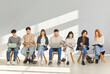 © Studio Romantic - Young people with backpacks, notebooks and laptops sitting in lobby. Male and female fresher or graduate students waiting in line for job interview to use youth internship staff recruiting opportunity