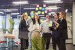 © Studio Romantic - Group of professionals working in modern office, using colorful sticky notes on glass board for brainstorming and collaborative planning. Company employees discussing business project during teamwork.