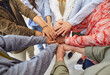 © Studio Romantic - Team of diverse people stacking their hands. Group of multiracial men and women holding hands together. Teamwork, friendship, support, community, cooperation concepts