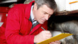 © IndigoElf - A worker in a red jacket is writing on a yellow clipboard, conducting an inspection. Home inspection, documentation, recording, professional