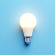 © NisatFarjana - Illuminated white L E D light bulb with silver base on a solid light blue background representing ideas and innovation