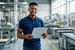 © f_bossa - A smiling young man in a blue polo shirt confidently poses with a clipboard in a modern industrial setting.