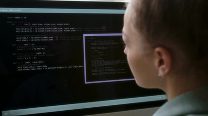 Close up of ambitious female programmer typing code while sitting at work desk in office