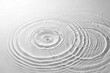© Graphics - A serene and minimalist view of gentle concentric water waves expanding from two impact points, creating an elegant interference pattern on a clear surface.