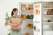 © Pixel-Shot - Beautiful woman with bag of food near open fridge in kitchen