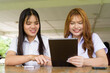 © Ranta Images - Young Thai University Students Relaxing Together at Campus Cafe Outdoors Using Tablet Computer