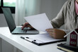 © Ople - A young woman real estate service worker is sitting at a computer searching for information and arranging house rentals for clients with care and professionalism