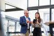 © David - Two business people reading papers together in modern office