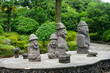 © Raisa - Several stone grandfather statues on Jeju Island in South Korea with forest in background