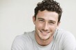 © Supanat - Smiling young man with curly hair and white shirt in bright indoor setting.