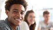 © Supanat - Smiling young African American man in casual clothing with diverse friends indoors.