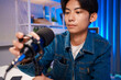 © ijeab - Young man adjusting microphone for podcast recording in home studio