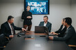 © qunica.com - Business people participating in a hybrid meeting with online colleagues shown on a screen. Collaborative discussion takes place in a modern office setting with laptops and technology enhancing