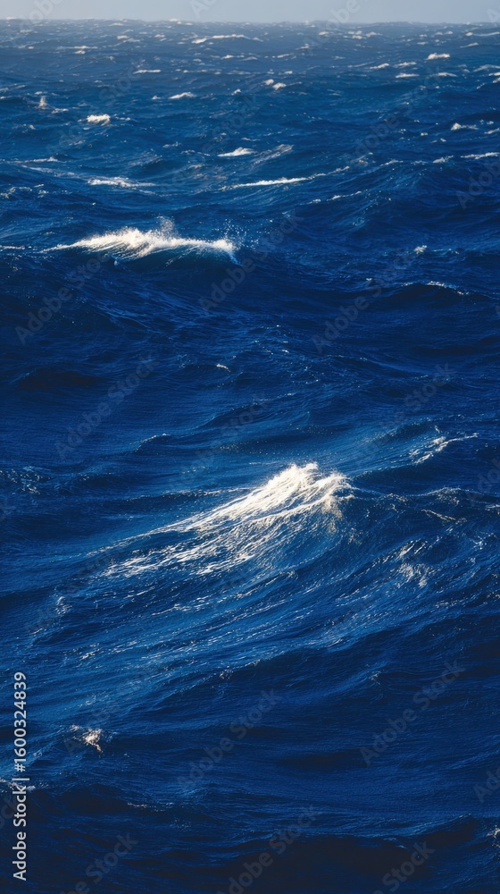 Rolling waves create a dynamic spectacle in the deep blue ocean. Sunlight glints off the water surface, highlighting varying shades of blue and creating a vibrant, lively atmosphere.