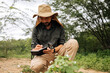 © kleberpicui - Male biologist writing in notebook while observing plants in natural environment