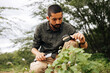 © kleberpicui - Concentrated male botanist examining plant with magnifying glass and taking notes outdoors