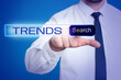 © New Africa - Businessman using virtual screen to find hot tendencies, new ideas, popular directions against blue background, closeup. Search bar with word Trends