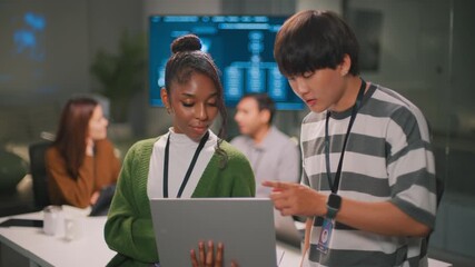 Focused African American woman leader and programmer in modern diverse office showing professional collaboration with her male colleague. Confident teamwork analyzing code