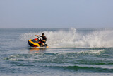Young man speeds on a jet ski under the bright summer sun. Concept freedom, adrenaline, and water thrill