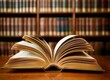 © Luqman - An open book with pages turning, set on an empty table in front of shelves filled with books. The background is blurred to emphasize the focus and texture of the open book. This scene symbolizes knowl
