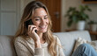 © Rhony - A beautiful smiling young woman talking with relatives on mobile phone while sitting on sofa at home.