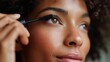 © fotofabrika - Woman applying mascara in front of a mirror during morning beauty routine in a well-lit bathroom