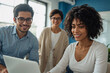 © Masud - Diverse team collaborating on a laptop in a bright office setting