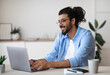 © Prostock-studio - Smiling western freelancer guy working on laptop at home office, sitting at desk using computer, young indian man in eyeglasses typing on keyboard, looking at screen, enjoying remote work, copy space