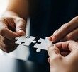 © picturehome - Close up view of two hands holding white pieces of jigsaw, trying to fit puzzle pieces together to overcome challenge, find solution, developing business plan or strategy. Companies merging, synergy
