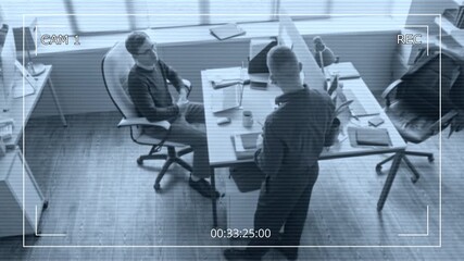 Wall Mural - Security camera footage of male office worker chatting with colleague discussing job tasks while sitting at desk with laptop in modern workspace