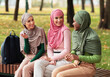 © Prostock-studio - Three Diverse Muslim Ladies In Hijab Talking Enjoying Conversation And Autumn Day Sitting On Bench In City Park. Modern Islamic Female Students Spending Time Chatting Outdoors