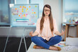 © WavebreakMediaMicro - Woman meditating with hands resting on knees on desk in modern office with whiteboard notes