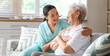 © Pixel-Shot - Physical therapist hugging senior woman on sofa at home