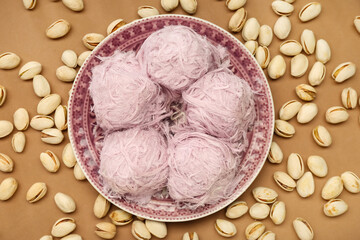 Wall Mural - Plate with tasty Turkish Pismaniye and pistachios on brown background