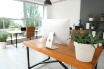 Wall Mural - blurred view of workplace with computer and plant