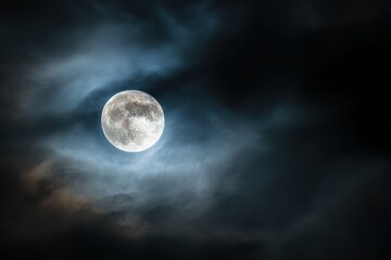 full moon glows through clouds in the dark night sky, creating a celestial scene