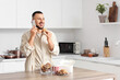 © Pixel-Shot - Young man with paw shaped cookie talking by mobile phone in kitchen