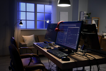 Wall Mural - programmer's desk with computer monitors and glowing lamps in dark office at night