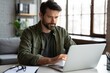 © Vivid Frame - Focused Man Working on Laptop at Desk in Home Office