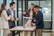 © aekachai - Group of business people are standing in a meeting presenting their work at the office.