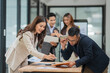 © aekachai - Group of business people are standing in a meeting presenting their work at the office.