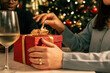 © Lomb - A woman's hands opening a Christmas gift. A moment of surprise and anticipation while unwrapping a present at a holiday party. The joy of receiving a gift from a loved one.
