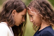 © Cavan Images - Two teenage twin girls look into each other's eyes